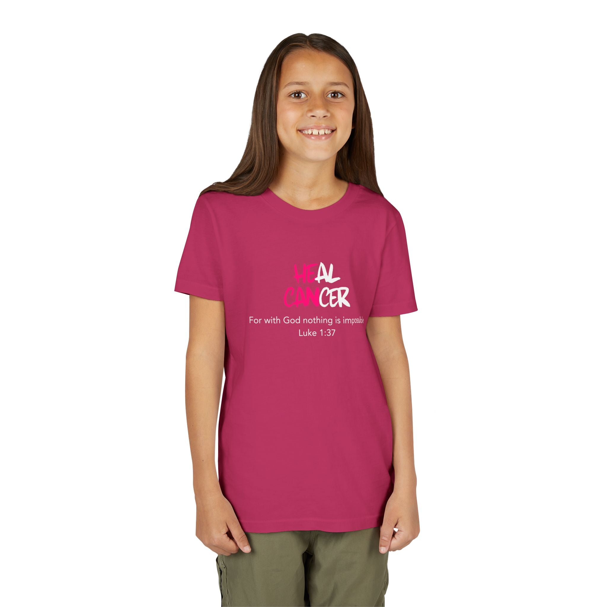 A young girl with long brown hair stands against a plain white background wearing a magenta pink t-shirt with a white and pink graphic that reads and 'For with God nothing is impossible Luke 1:37'.