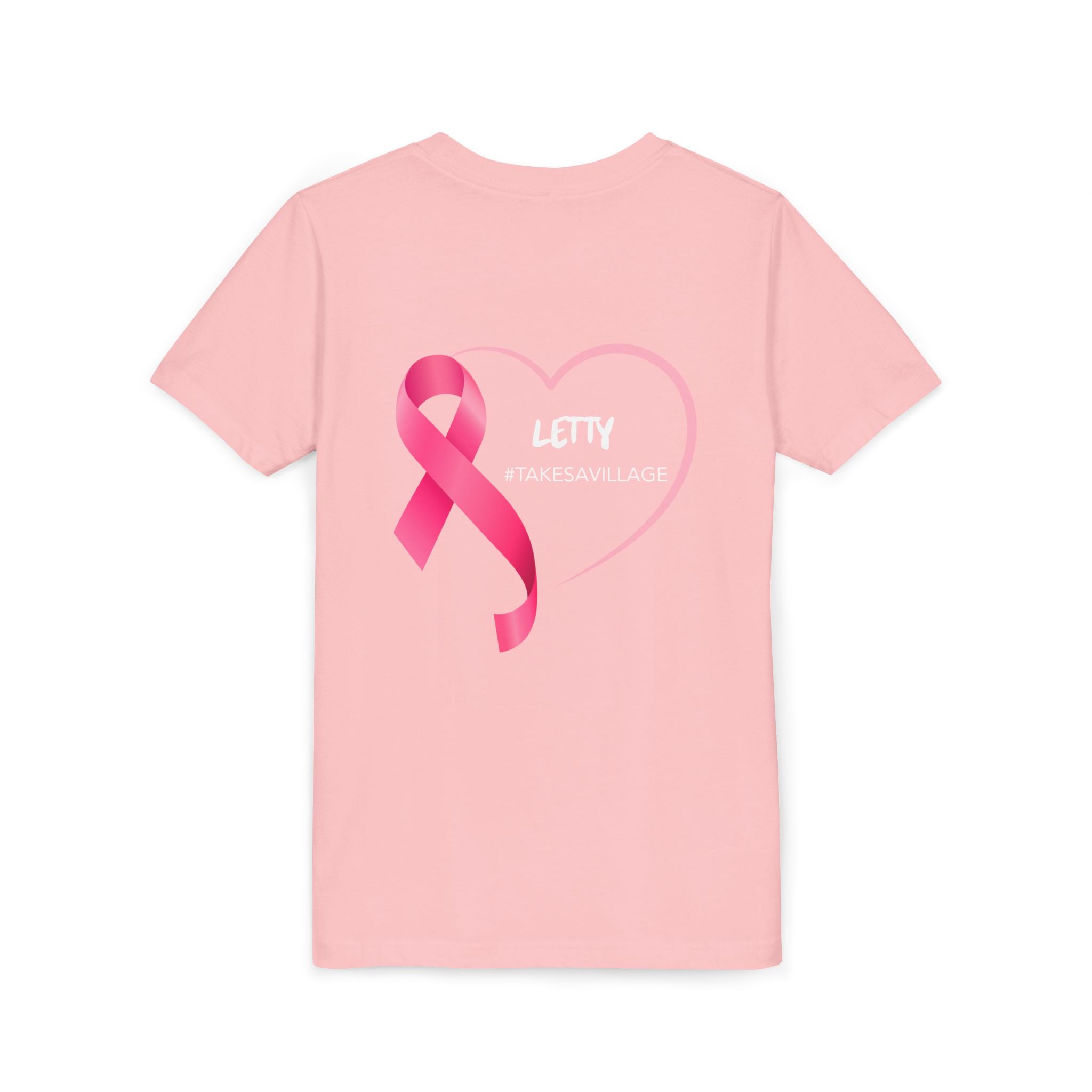 A light pink short-sleeve t-shirt with a pink ribbon and heart graphic on the front, featuring the text 'LETTY #TAKESAVILLAGE' in white, displayed on a clean white background.